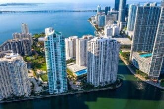 An aerial view of Brickell and Brickell Key in Miami, showcasing high-rise buildings, waterways, and a distant bridge.