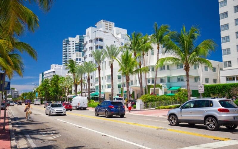 Photo of Collins Avenue in Miami Beach featuring historic Art Deco buildings in the background.