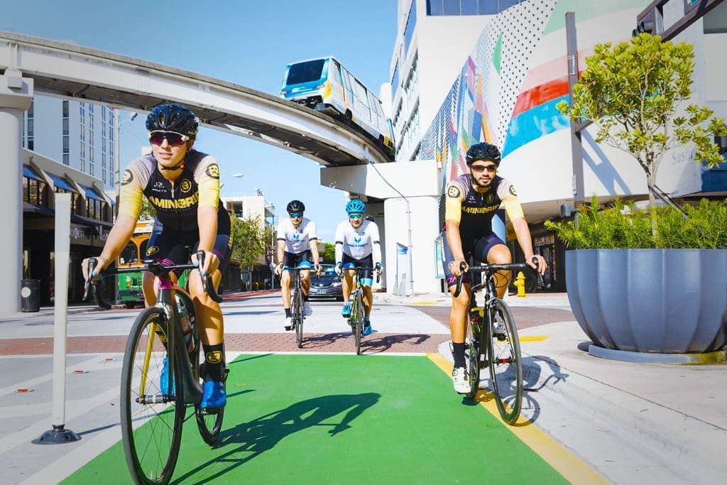 A group of cyclists navigates Downtown's urban landscape, with the Metromover in the background