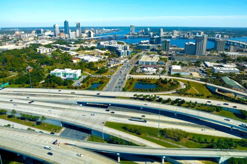 Aerial view of Jacksonville, FL with high-rise office buildings and intersecting American freeways bustling with cars and trucks