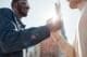 A close-up side view of two men shaking hands as they greet each other outdoors in a sunlit Floridian city