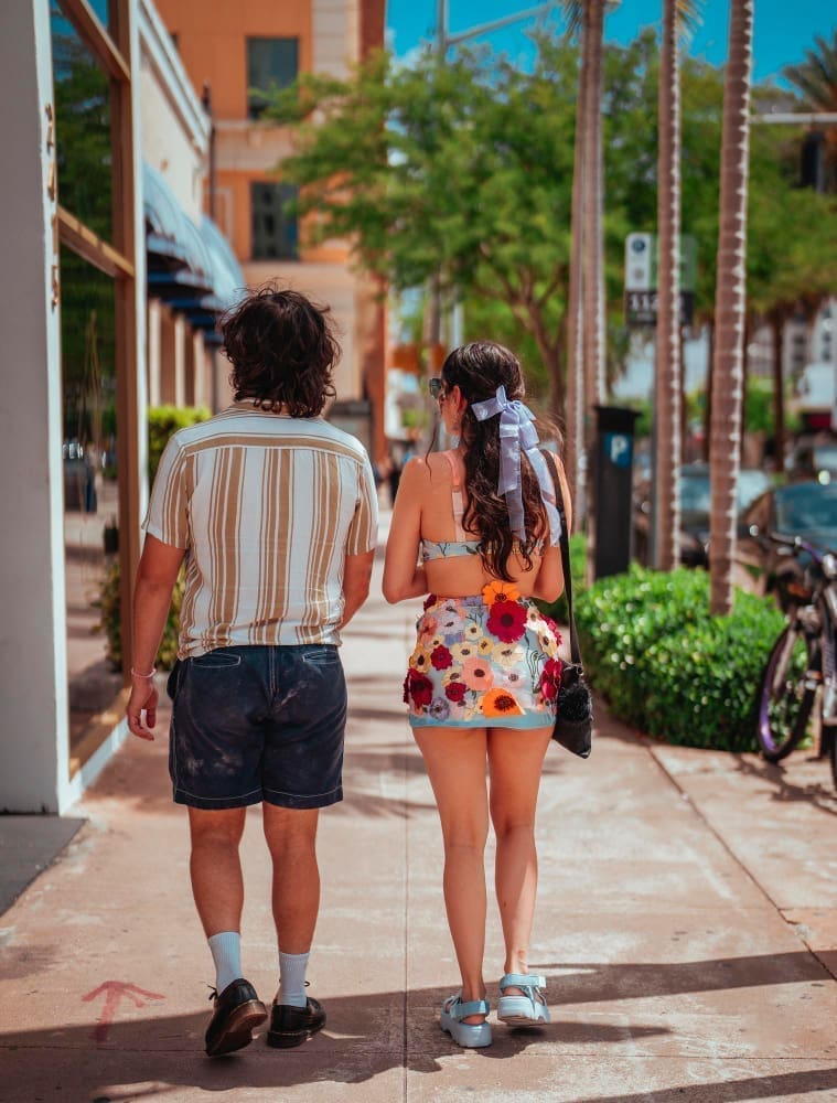 A couple strolls along the sidewalk, window shopping through the stores in Coconut Grove