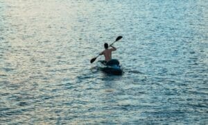 A man paddles his kayak through the waters of Coconut Grove in the early morning