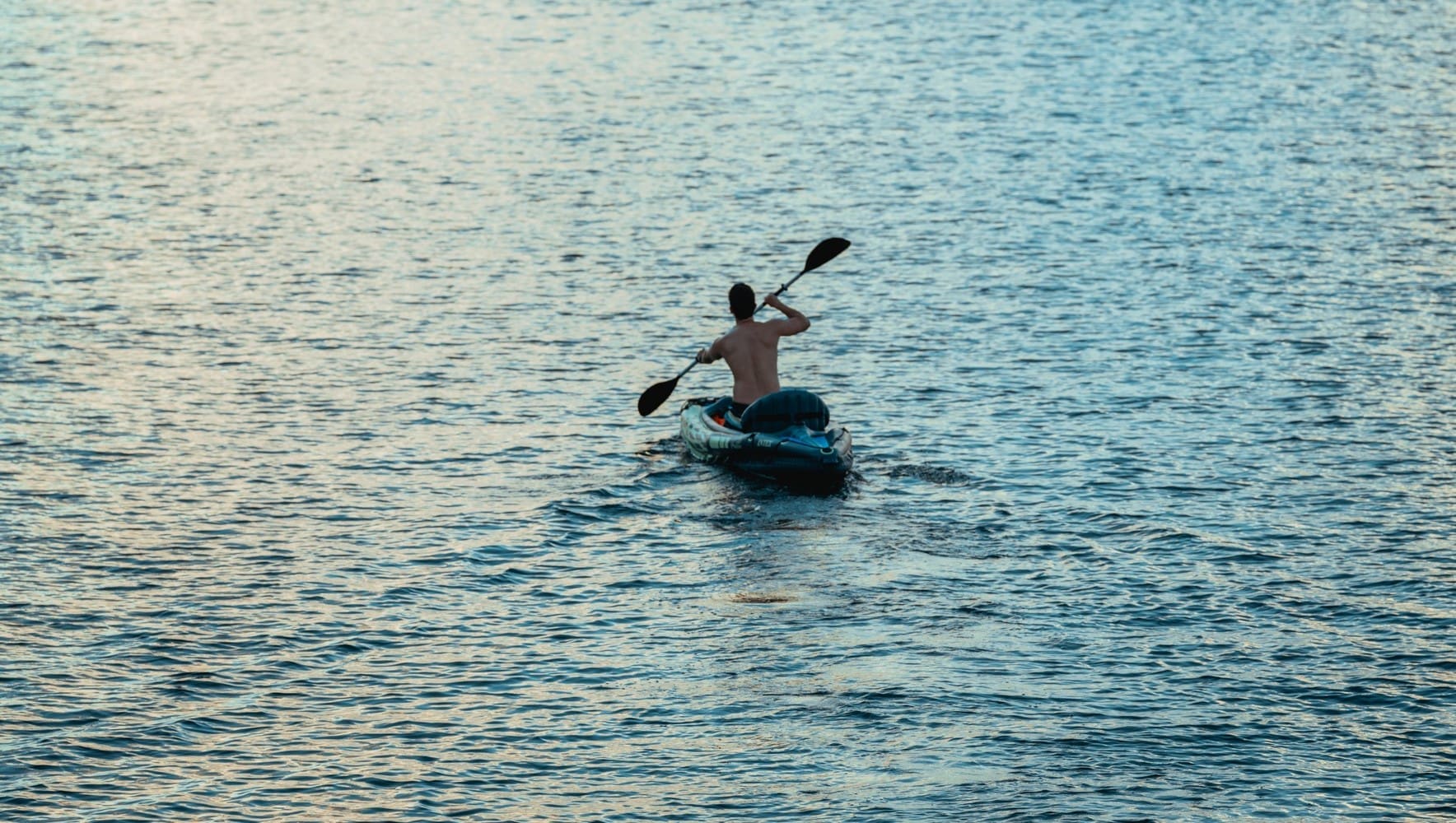 A man paddles his kayak through the waters of Coconut Grove in the early morning