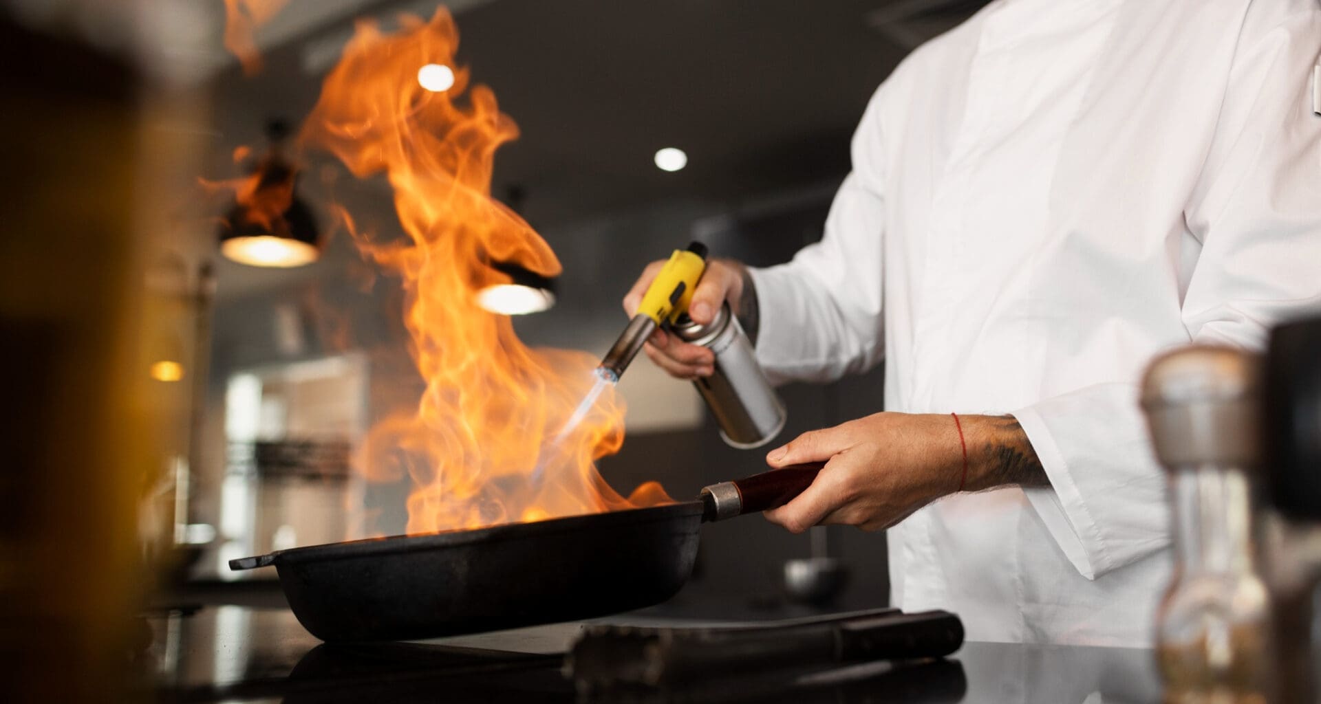 A chef is cooking in the kitchen of a restaurant, seen from the side