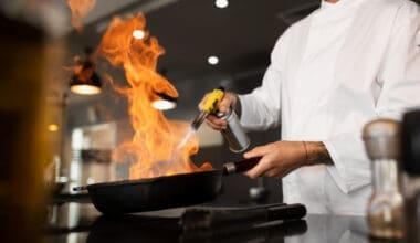 A chef is cooking in the kitchen of a restaurant, seen from the side