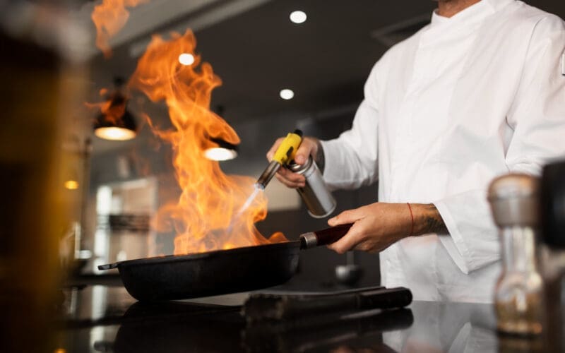 A chef is cooking in the kitchen of a restaurant, seen from the side