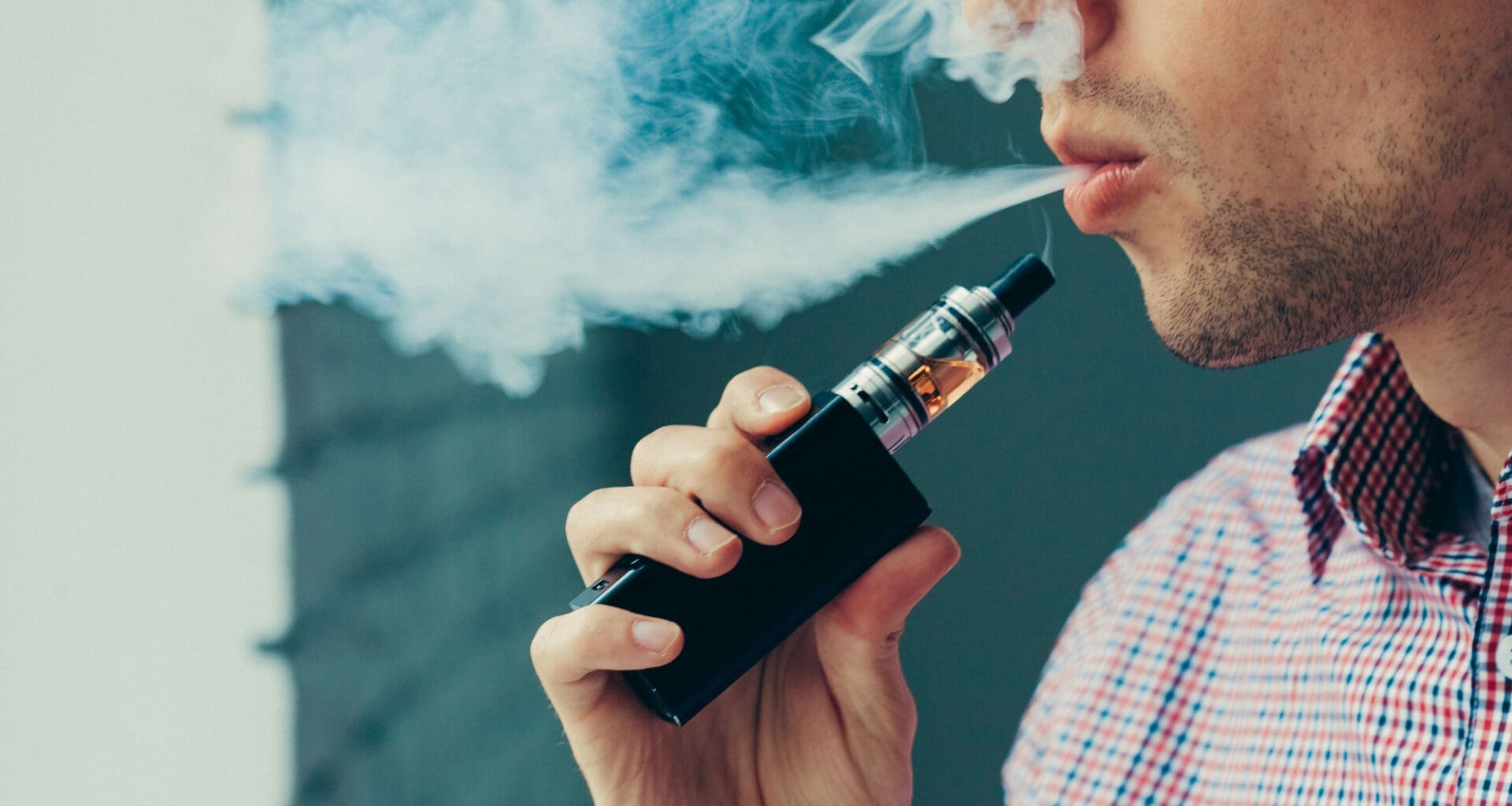 A man takes a deep breath and exhales a cloud of vapor from his electronic cigarette