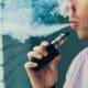 A man takes a deep breath and exhales a cloud of vapor from his electronic cigarette