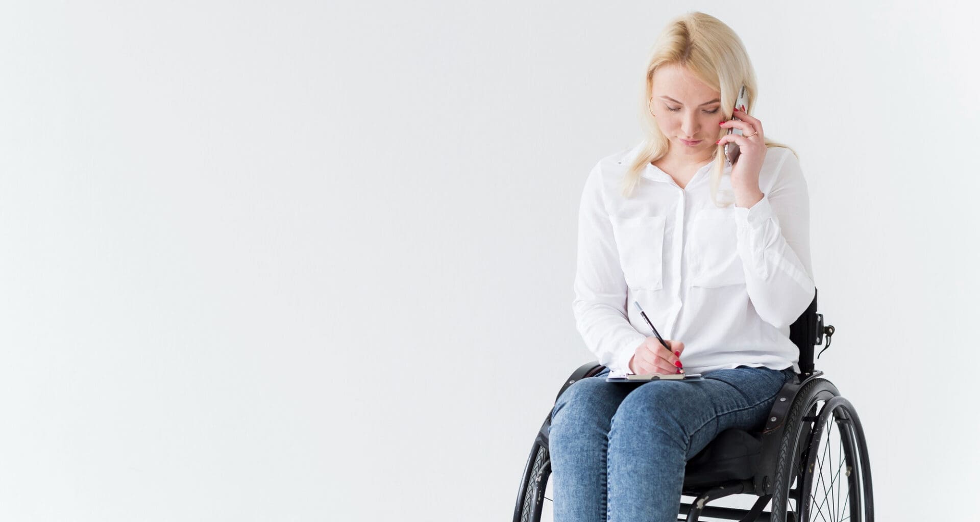 A woman with multiple sclerosis is seen from the front, sitting in a wheelchair as she works and talks on the phone