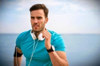 Close-up of a young, fit man jogging along the shoreline
