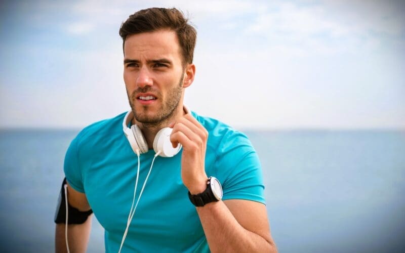 Close-up of a young, fit man jogging along the shoreline