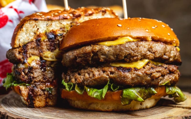 Side view of a double cheeseburger with beef patties, cheese, and lettuce