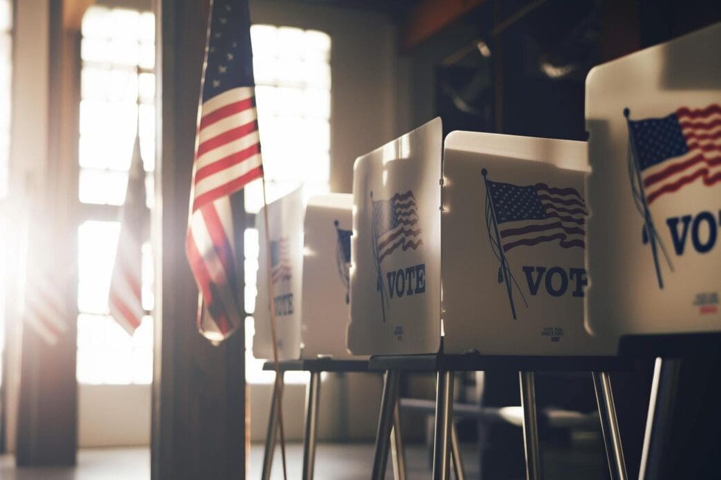 Voting stations neatly arranged against a wall decorated with US flags