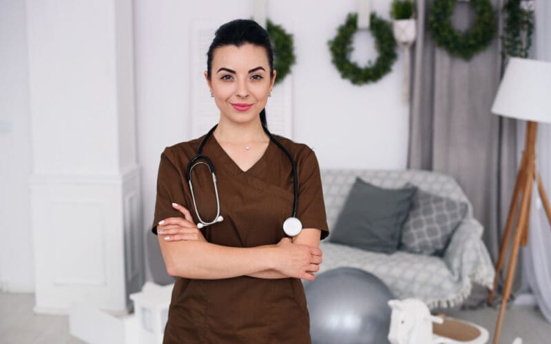 Smiling friendly children's doctor woman with stethoscope wearing brown medical robe health care medical concept