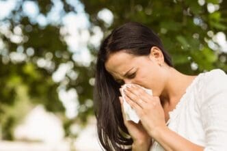 A brunette woman is blowing her nose due to her allergies