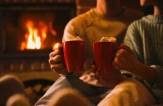 A charming couple enjoying sweet cocoa by the fireplace indoors, captured in a close-up shot