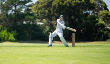 A cricketer is batting on a green cricket oval during a local match in the summer heat of Australia