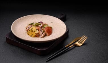 A delectable, fresh salad featuring sliced chicken, grapefruit, lettuce, and sesame, elegantly drizzled with olive oil, served on a ceramic plate