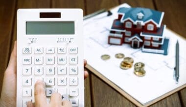 A female hand operating a calculator in front of a Villa house model