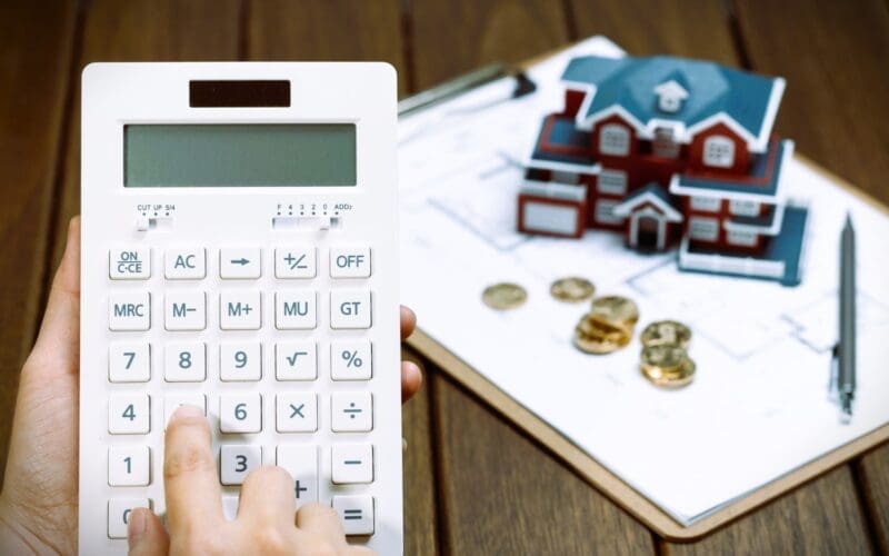 A female hand operating a calculator in front of a Villa house model