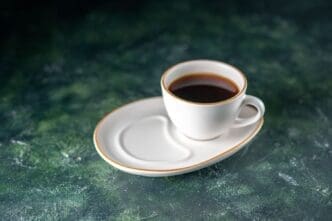 A front view of a cup of tea on a white plate resting on a dark surface, perfect for a ceremonial breakfast in the morning