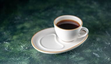 A front view of a cup of tea on a white plate resting on a dark surface, perfect for a ceremonial breakfast in the morning