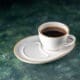 A front view of a cup of tea on a white plate resting on a dark surface, perfect for a ceremonial breakfast in the morning