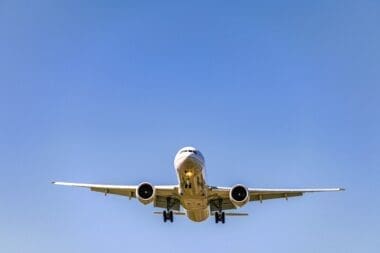 A low-angle shot of an airplane soaring overhead during the day