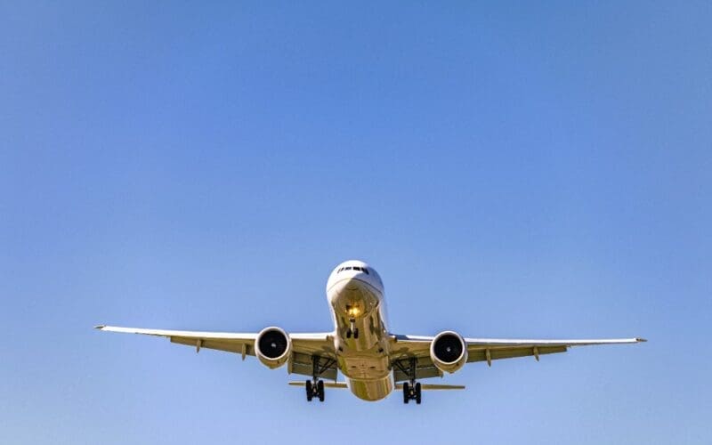 A low-angle shot of an airplane soaring overhead during the day