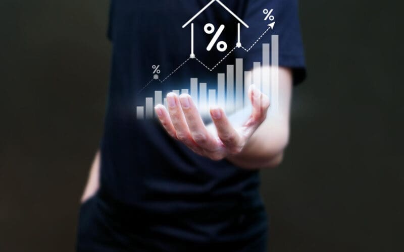 A man's hand interacting with a data analytics graph displayed on a virtual screen, symbolizing the concept of real estate investment