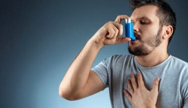 A portrait of a man gripping his asthma inhaler, experiencing an asthmatic attack.