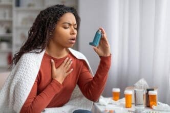 A young Black woman using her inhaler to find relief during an asthma attack