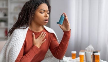 A young Black woman using her inhaler to find relief during an asthma attack