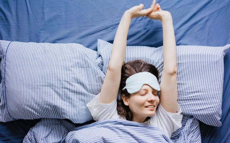 A young woman awakens in bed, feeling refreshed after a peaceful night’s sleep.