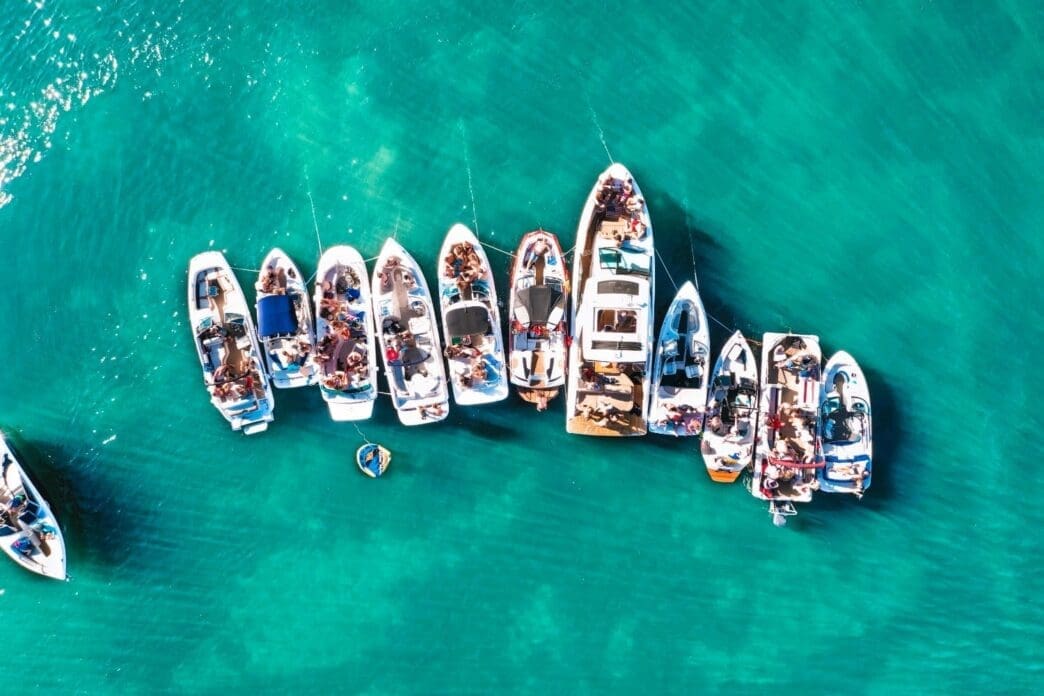 Aerial drone view capturing various sizes of boats anchored near the beach of an island in Biscayne Bay