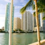 An elderly man relaxes on a bench by Biscayne Bay, taking in the view of the Brickell skyline