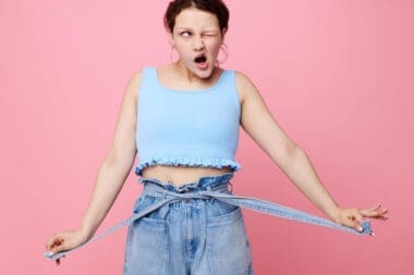 Close-up of a funny girl making a grimace, showcasing her emotions about weight loss while posing with earrings—authentic lifestyle moment.