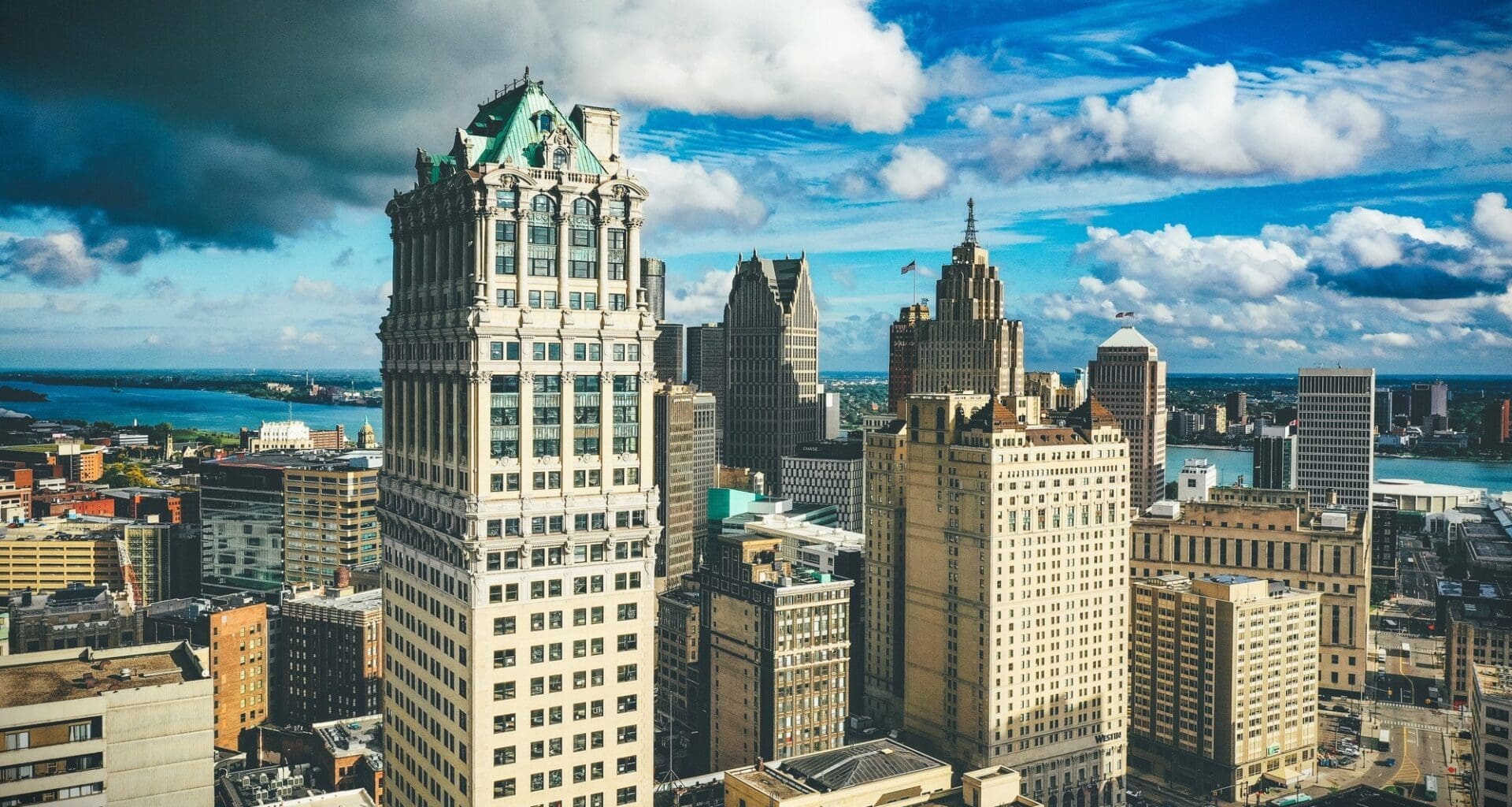 Detroit's skyline illuminated by sunlight contrasts sharply with a dark, overcast sky during the day