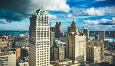 Detroit's skyline illuminated by sunlight contrasts sharply with a dark, overcast sky during the day