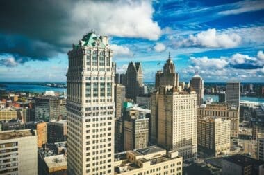 Detroit's skyline illuminated by sunlight contrasts sharply with a dark, overcast sky during the day