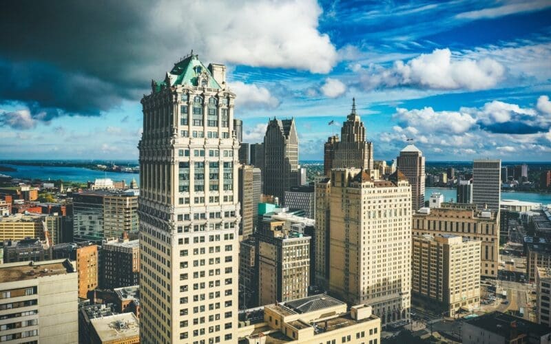 Detroit's skyline illuminated by sunlight contrasts sharply with a dark, overcast sky during the day