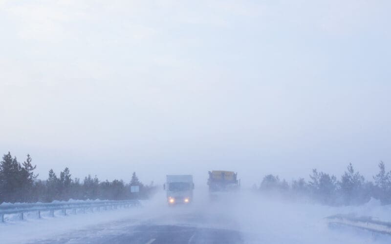 Highway featuring trucks navigating through severe winter weather