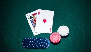 Jack of Spades and Ace of Hearts cards alongside a stack of casino chips on a green poker table