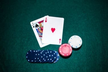 Jack of Spades and Ace of Hearts cards alongside a stack of casino chips on a green poker table