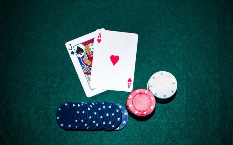 Jack of Spades and Ace of Hearts cards alongside a stack of casino chips on a green poker table