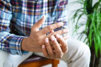 Man experiencing finger pain while seated, due to rheumatoid arthritis