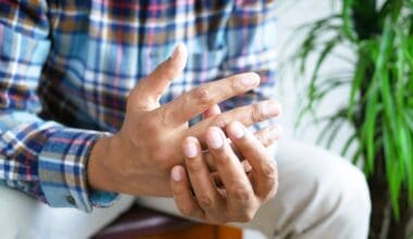 Man experiencing finger pain while seated, due to rheumatoid arthritis