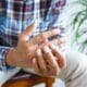 Man experiencing finger pain while seated, due to rheumatoid arthritis