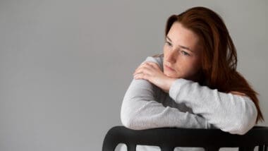 Medium shot of a woman sitting in a chair, looking visibly depressed